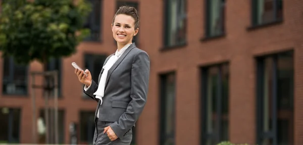 Glückliche moderne Geschäftsfrau mit Handy im Büroviertel — Stockfoto