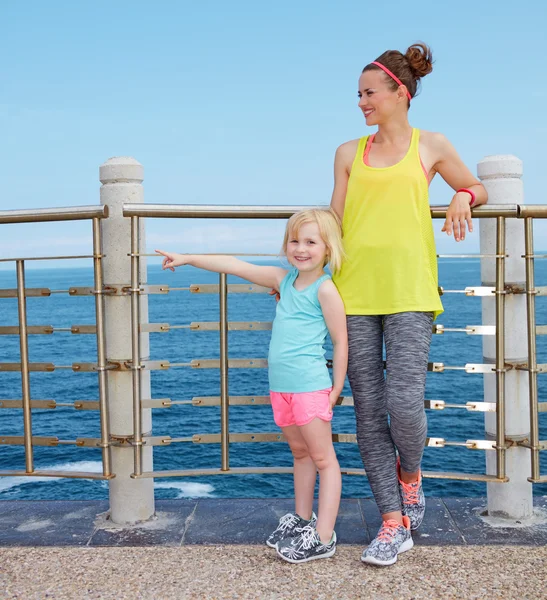 Fitness madre e hijo en terraplén apuntando a algo — Foto de Stock