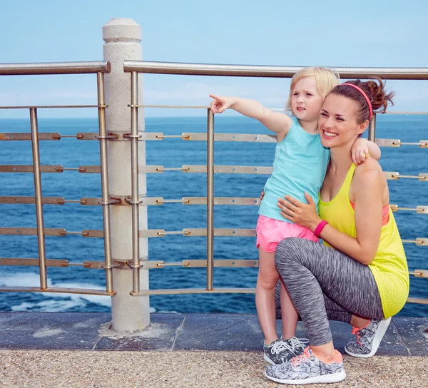 Fitness moeder en kind aan kade wijzen op iets — Stockfoto