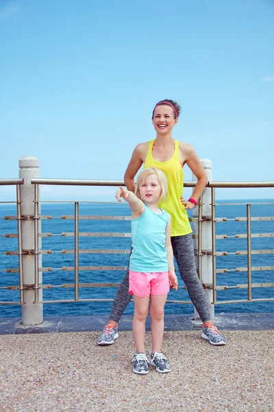 Fitness moeder en kind aan kade wijzen op iets — Stockfoto