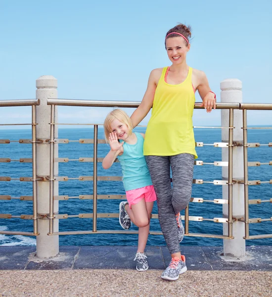 Fitness matka a dítě stojící na nábřeží a handwaving — Stock fotografie