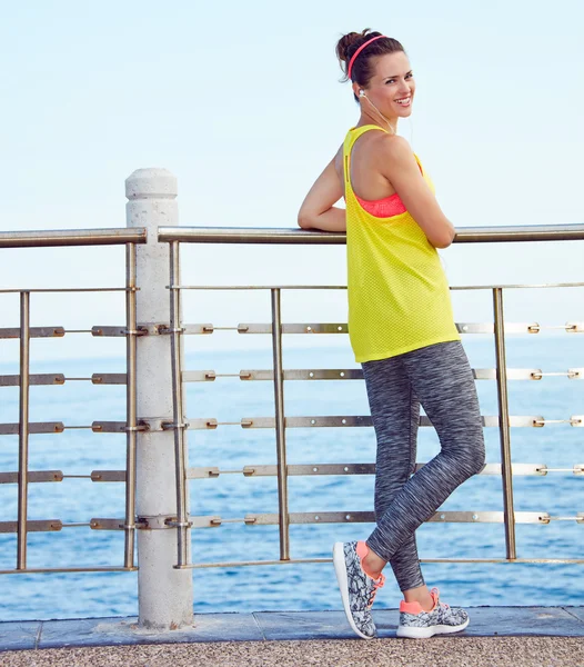 Full length portrait of happy fit woman standing at embankment — Stock Photo, Image