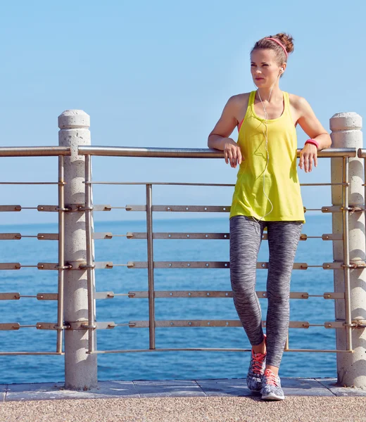 Frau im Fitness-Outfit blickt an Böschung in die Ferne — Stockfoto