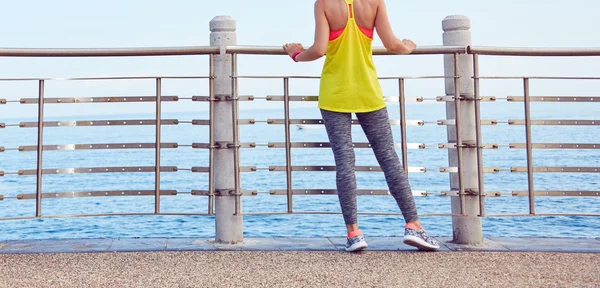 Young woman in fitness outfit standing at embankment — Stock Photo, Image