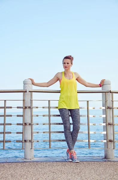 Young woman in fitness outfit looking aside at embankment — Stock Photo, Image