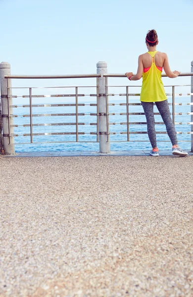 Young woman in fitness outfit standing at embankment — Stock Photo, Image
