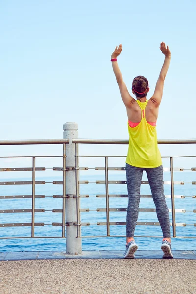 Relaxed young woman in fitness outfit rejoicing at embankment — Stock Photo, Image