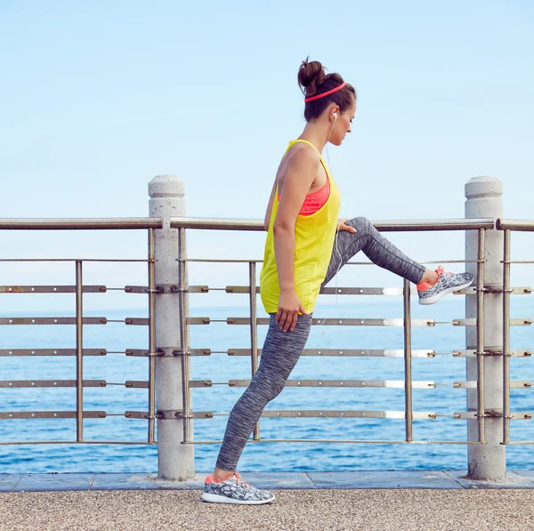 Young healthy woman in fitness outfit stretching at embankment — Zdjęcie stockowe