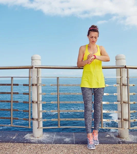 Young athlete using smart bracelet sport watch at embankment — Stock Photo, Image