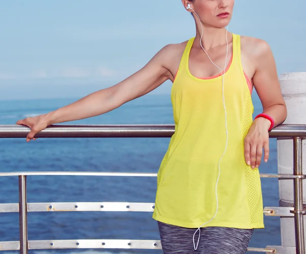 Woman in fitness outfit looking aside and listening to music — ストック写真