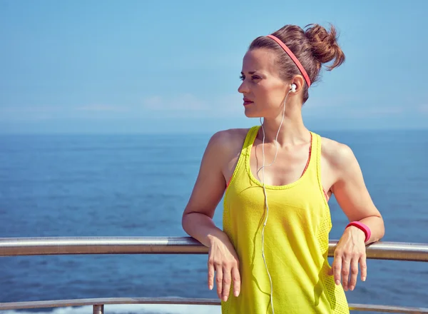 Fitness vrouw op zoek naar afstand en luisteren naar muziek — Stockfoto