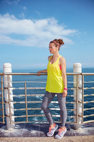 Junge Frau im Fitness-Outfit blickt auf Böschung — Stockfoto