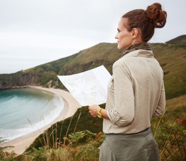woman hiker with map in front of ocean view landscape