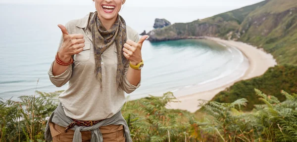 Woman hiker showing thumbs up in front of ocean view landscape — Stock fotografie