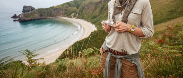 Felice donna escursionista scrittura sms di fronte al paesaggio vista oceano — Foto Stock