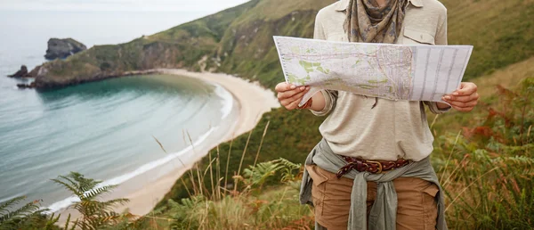 Woman hiker looking at map in front of ocean view landscape — Stock Photo, Image