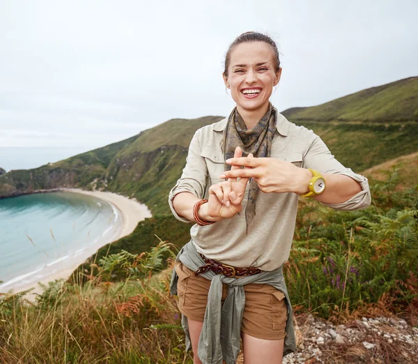 Excursionista mostrando gesto hashtag frente al paisaje vista al mar — Foto de Stock