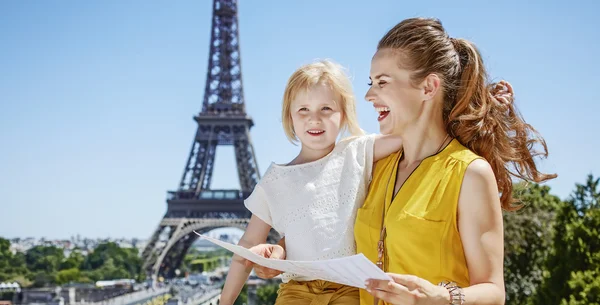 Feliz madre e hija sosteniendo mapa contra la torre Eiffel —  Fotos de Stock