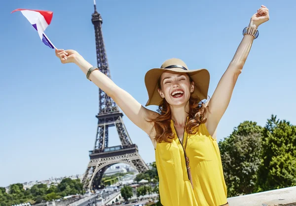 Gelukkige jonge vrouw stijgende vlag in de voorkant van de Eiffel toren in Parijs — Stockfoto