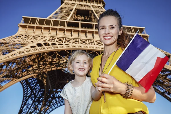 Madre e hija turistas mostrando bandera contra la torre Eiffel — Foto de Stock
