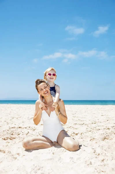 Szczęśliwą matką i dziewczyny w strojach kąpielowych przy piaszczystej plaży w słoneczny dzień — Zdjęcie stockowe