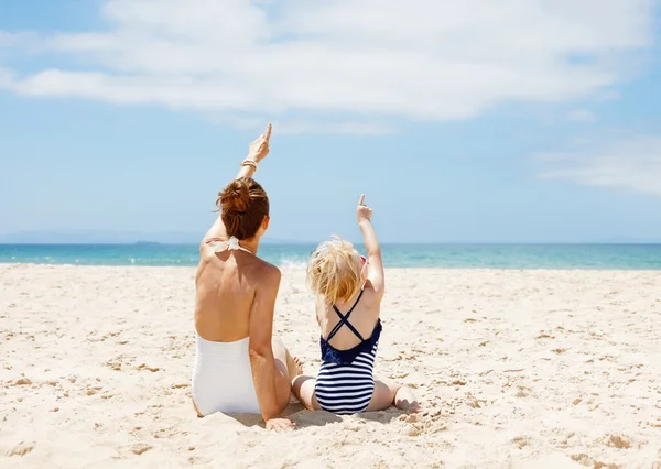 Δει πίσω από τη μητέρα και το παιδί δείχνει προς τα επάνω στην αμμώδη παραλία — Φωτογραφία Αρχείου