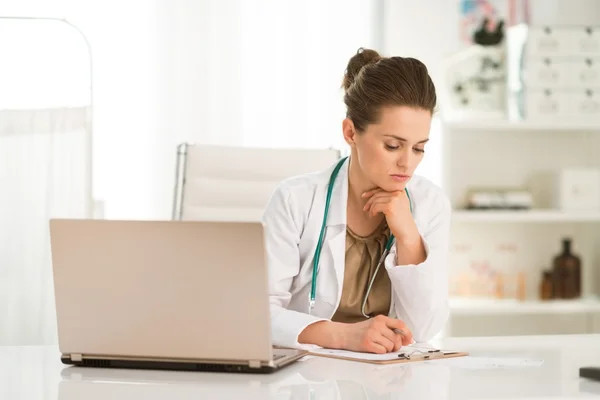 Thoughtful female doctor sitting at a desk in the office — Stock Photo, Image