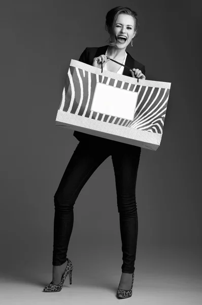 Kobieta z duża torba na zakupy mrugając na szarym tle — Zdjęcie stockowe