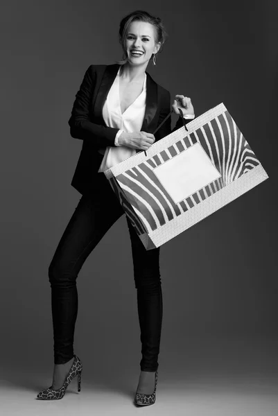 Happy woman showing big shopping bag against grey background — Stock Photo, Image