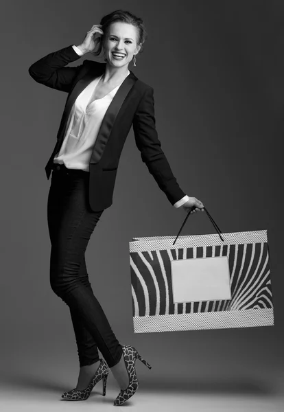 Mujer feliz con gran bolsa de compras sobre fondo gris —  Fotos de Stock