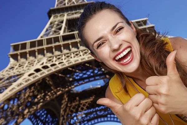 Glimlachend jonge vrouw duimen opdagen voor de Eiffeltoren — Stockfoto