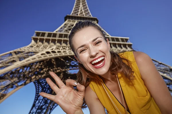 Usmívající se žena ukazuje ok gesto před Eiffel tower, Paříž — Stock fotografie