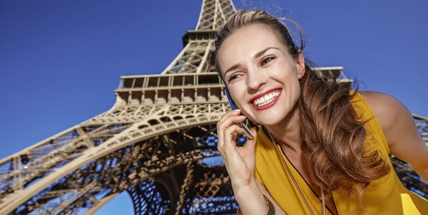 Jeune femme heureuse utilisant un téléphone portable contre la tour Eiffel, Paris — Photo