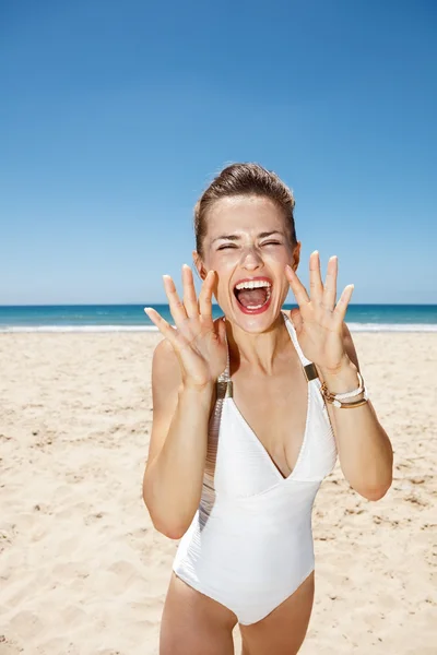 Donna urlando attraverso le mani a forma di megafono sulla spiaggia di sabbia — Foto Stock