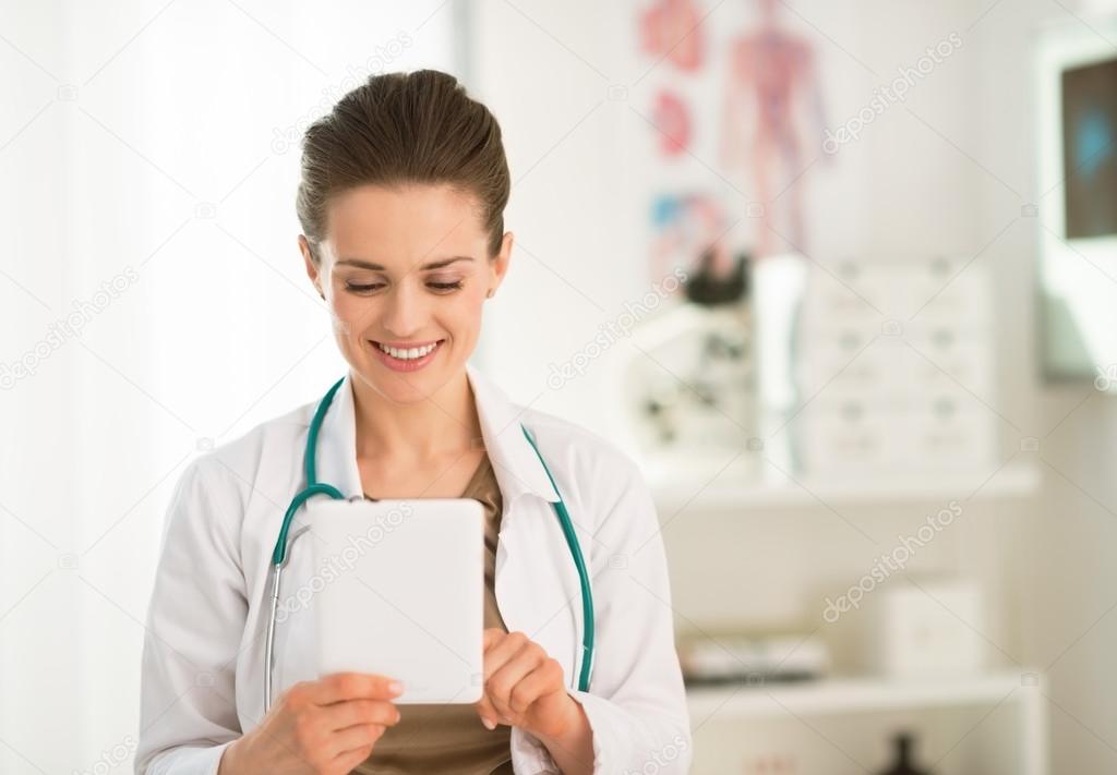 Happy female doctor in the office using tablet PC