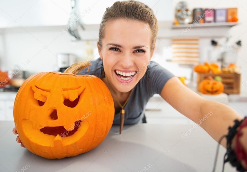 Smiling young woman taking selfie in halloween decorated kitchen