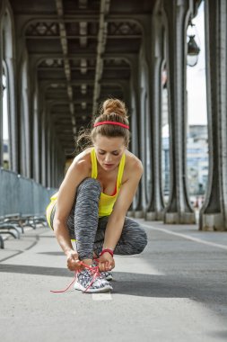 sporcumuz Paris Pont de Bir-Hakeim köprüde, ayakkabı bağcığı bağlama