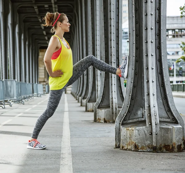 Sportvrouw die zich uitstrekt over de Pont de Bir-Hakeim brug in Parijs — Stockfoto