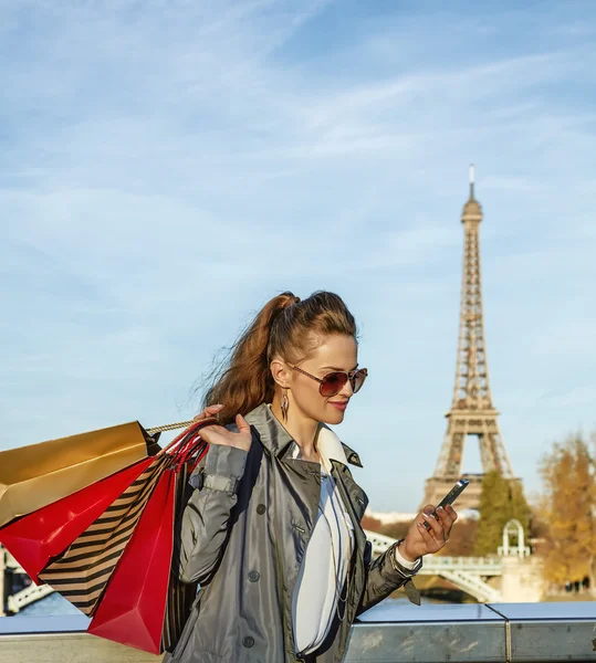 Moderní žena s nákupní tašky psaní sms blízko: Eiffel tower — Stock fotografie