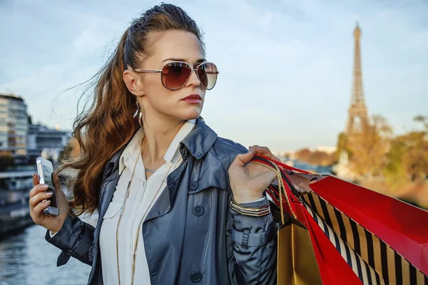 Femme avec sacs à provisions et smartphone à Paris regardant de côté — Photo