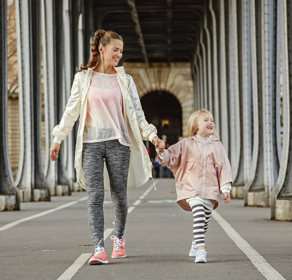 Smiling active mother and child on bridge in Paris going forward — Stock Photo, Image