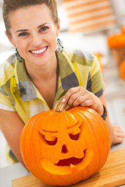 woman with a big orange pumpkin Jack-O-Lantern in kitchen