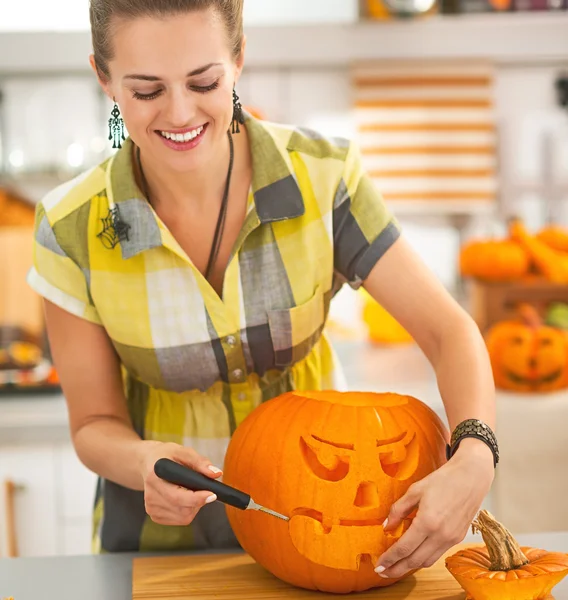 Happy housewife carving a big orange pumpkin Jack-O-Lantern — Stock Photo, Image