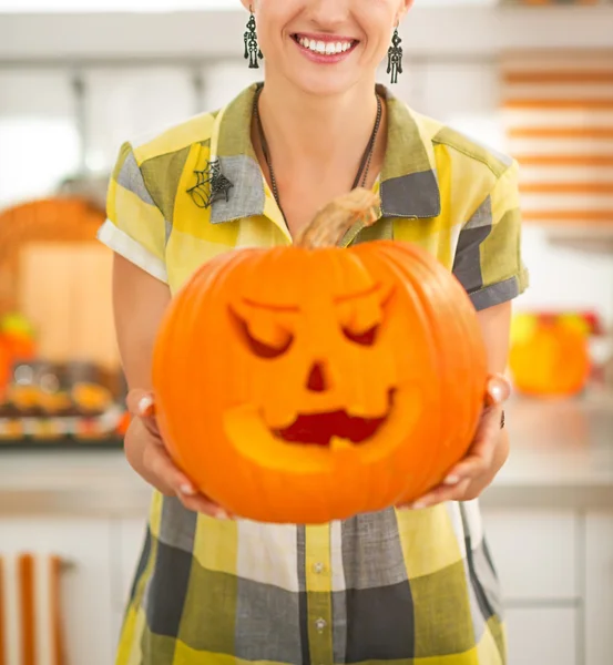 Dona de casa na cozinha mostrando grande abóbora Jack-O-Lanterna — Fotografia de Stock