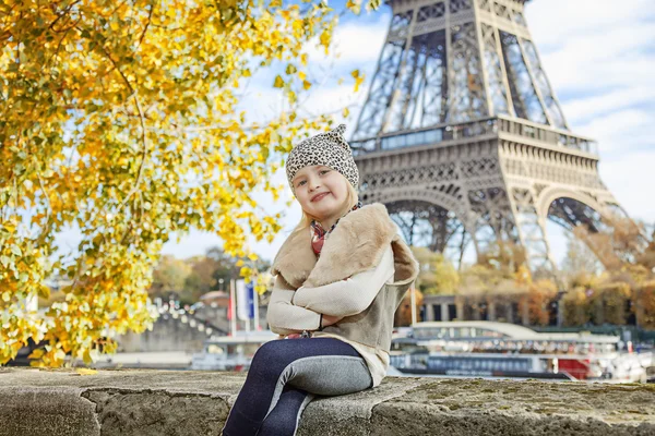 Elegáns gyermek ül a mellvéd töltésén Eiffel-torony közelében — Stock Fotó
