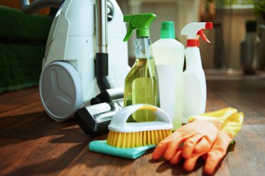 Elektrik süpürgesi, temizlik şişeleri, lastik eldivenler, yerdeki fırça ve temizlik bezleri..