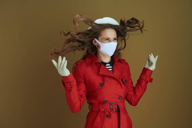 Covid-19 salgını sırasında hayat. Gülümseyen orta yaşlı, kırmızı ceketli, bronz arka planda soyutlanmış bir kadın..