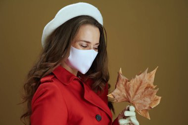 Merhaba sonbahar. 40 yaşında kırmızı ceketli, sarı sonbahar akçaağaç yaprağı kahverengi arka planda izole bir kadın..