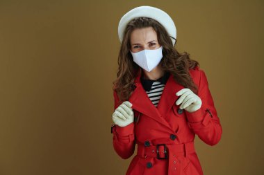 Koronavirüs salgını sırasında hayat. Gülümseyen modern 40 yaşındaki kırmızı ceketli ev kadınının portresi bronz arka planda..