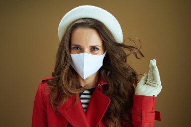 Koronavirüs salgını sırasında hayat. Bej arka planda izole edilmiş kırmızı ceketli orta yaşlı kadın portresi.